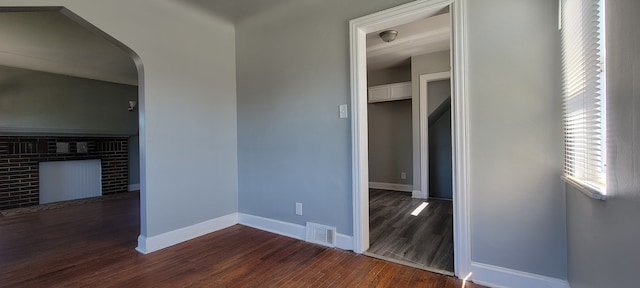 empty room with dark hardwood / wood-style flooring and a fireplace