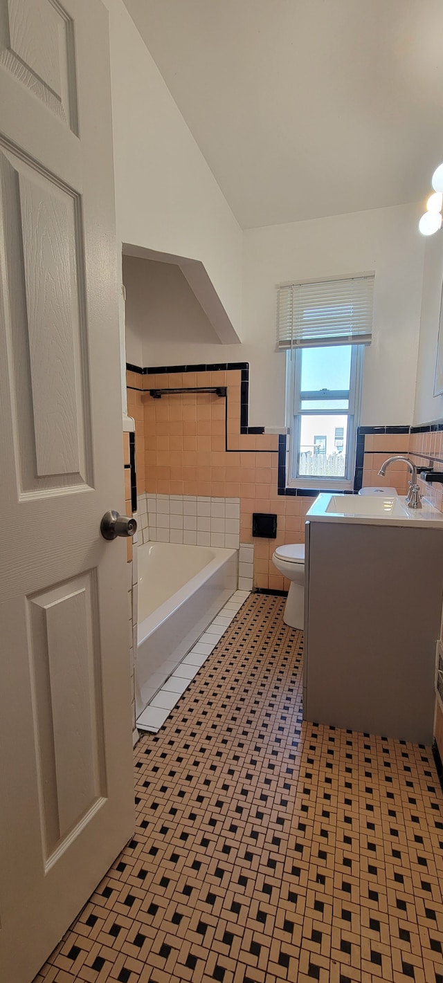 bathroom with a tub, tile walls, vanity, toilet, and tile patterned floors