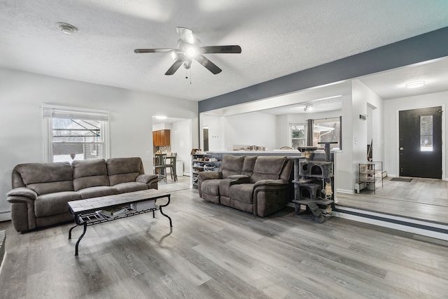 living room featuring ceiling fan, plenty of natural light, a textured ceiling, and light wood-type flooring