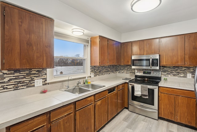 kitchen featuring tasteful backsplash, sink, light hardwood / wood-style floors, and appliances with stainless steel finishes