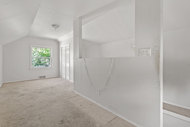 bonus room with vaulted ceiling and light colored carpet