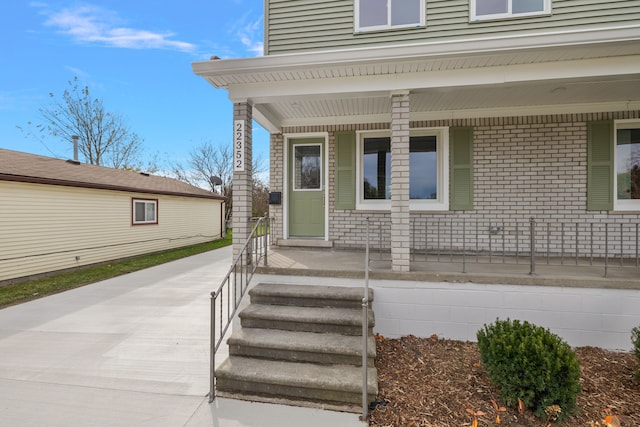 doorway to property with a porch and brick siding