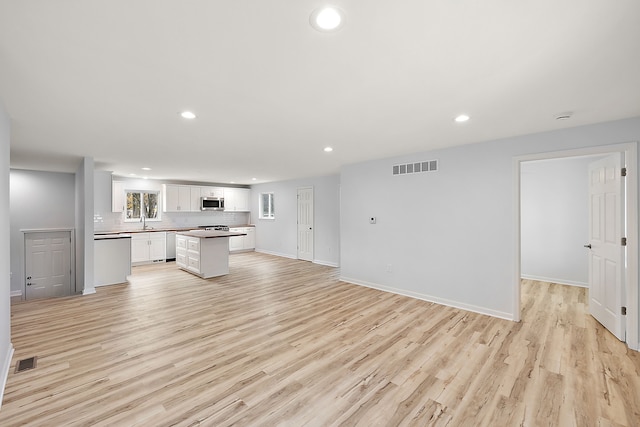 kitchen with open floor plan, stainless steel microwave, a sink, and visible vents