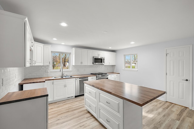 kitchen featuring stainless steel appliances, butcher block counters, a sink, and light wood-style flooring