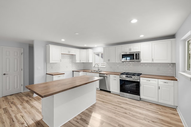 kitchen with stainless steel appliances, light wood-type flooring, plenty of natural light, and wood counters