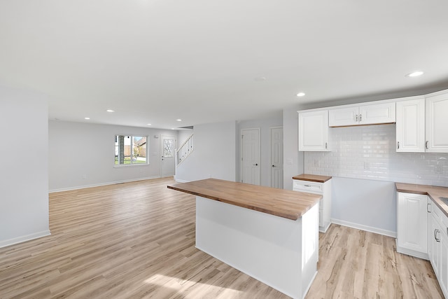 kitchen featuring light wood-style flooring, butcher block countertops, white cabinets, and backsplash