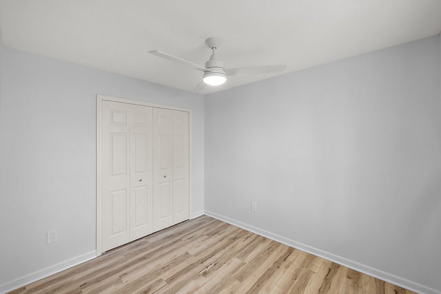 unfurnished bedroom featuring a closet, ceiling fan, light wood-style flooring, and baseboards