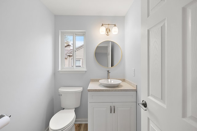 bathroom with wood finished floors, vanity, toilet, and baseboards