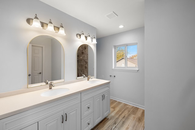 full bath featuring double vanity, visible vents, a sink, and wood finished floors