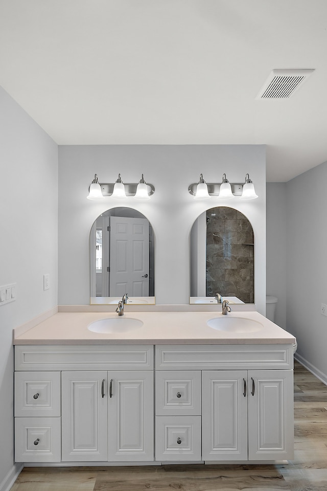 bathroom featuring double vanity, visible vents, a sink, and wood finished floors