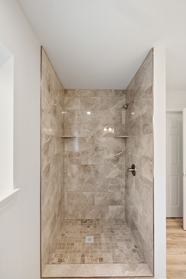 full bath with wood finished floors and a tile shower