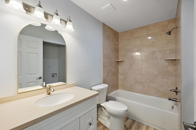 bathroom with toilet, wood finished floors, vanity, visible vents, and  shower combination