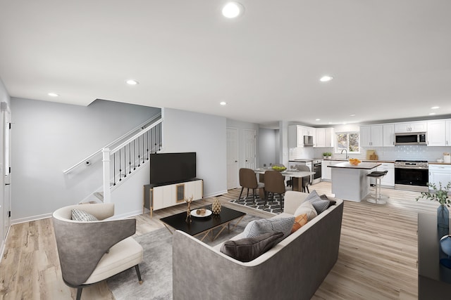 living room featuring stairs, baseboards, light wood-style flooring, and recessed lighting