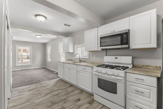 kitchen with light hardwood / wood-style floors, white range with gas stovetop, white cabinets, and sink