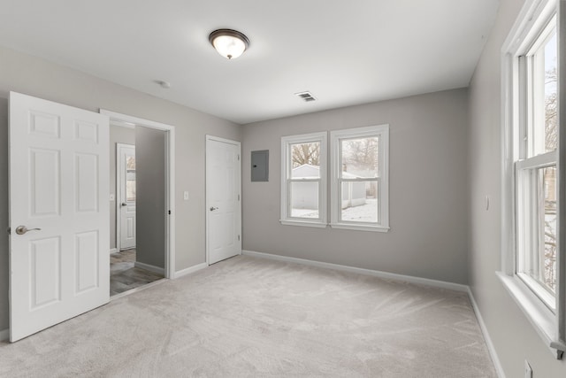 unfurnished bedroom featuring a closet, electric panel, and light carpet