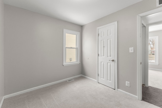 unfurnished bedroom with light colored carpet and multiple windows