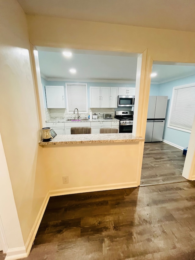 kitchen featuring sink, white cabinetry, backsplash, stainless steel appliances, and dark hardwood / wood-style floors