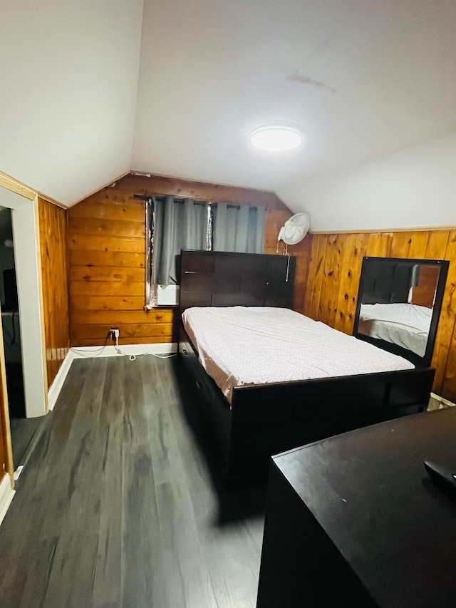 bedroom featuring vaulted ceiling, wooden walls, and dark hardwood / wood-style flooring