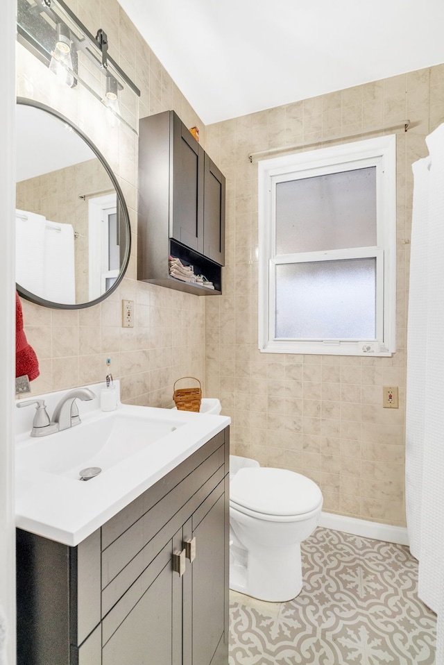 bathroom with vanity, toilet, and tile walls