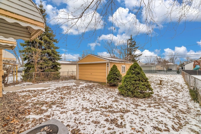 view of snowy exterior with a garage and an outbuilding