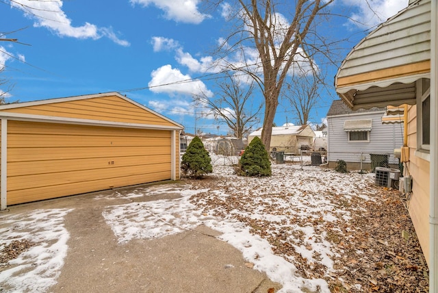 yard covered in snow with a garage, cooling unit, and an outdoor structure