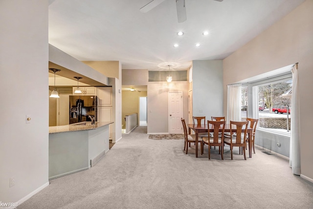 carpeted dining space with sink and ceiling fan