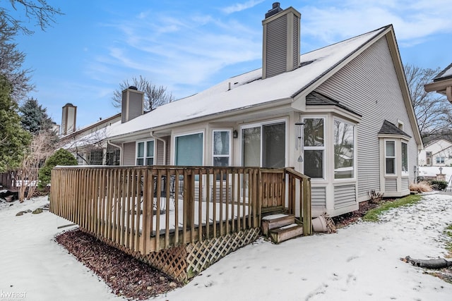 snow covered back of property featuring a wooden deck