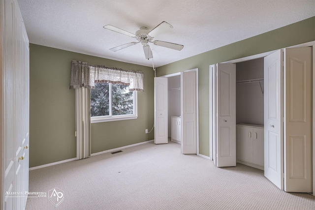 unfurnished bedroom featuring ceiling fan, light colored carpet, and a textured ceiling