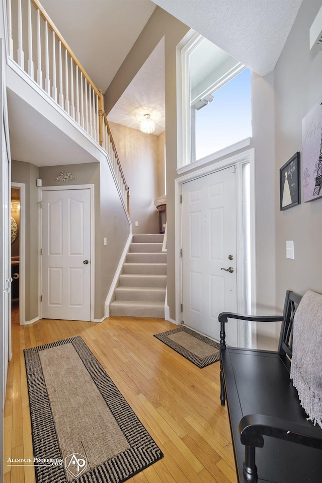 entryway with hardwood / wood-style floors and a towering ceiling