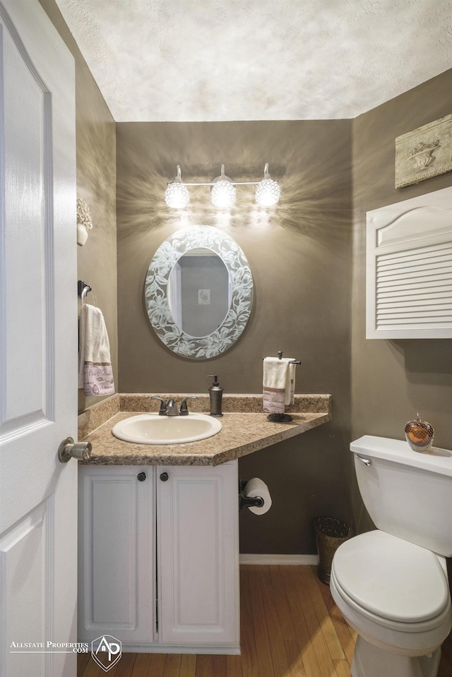 bathroom featuring a textured ceiling, hardwood / wood-style flooring, toilet, and vanity