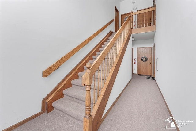 stairway featuring a towering ceiling and carpet flooring