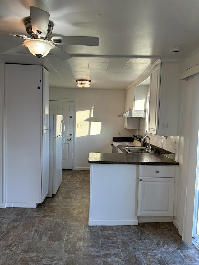 kitchen featuring white cabinetry, sink, kitchen peninsula, white refrigerator, and wall chimney exhaust hood