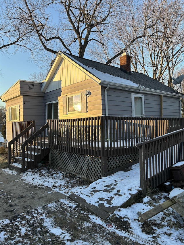 snow covered back of property featuring a deck