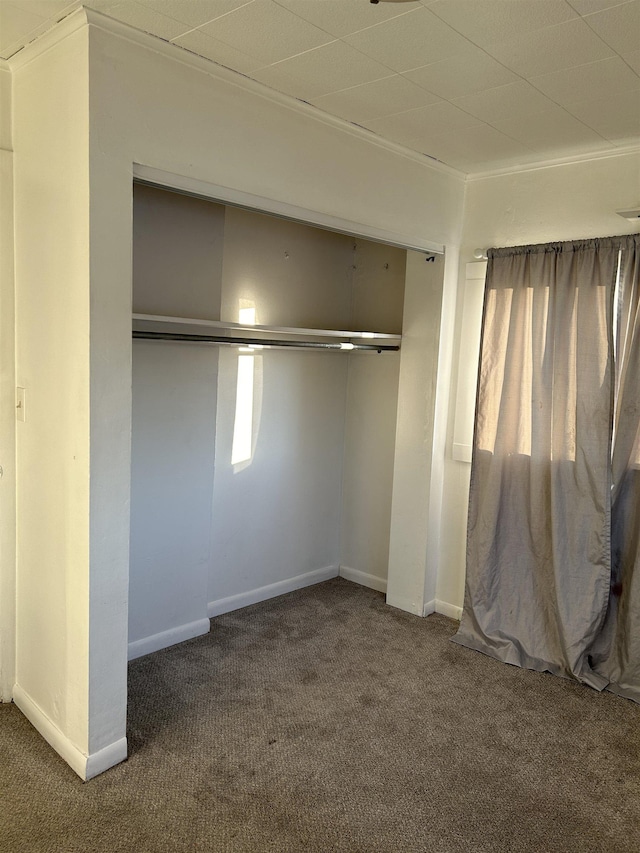 unfurnished bedroom with dark carpet and a closet