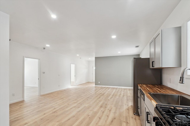 kitchen featuring sink, butcher block counters, stainless steel appliances, and light wood-type flooring