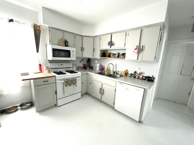 kitchen with tasteful backsplash, white appliances, sink, and gray cabinetry