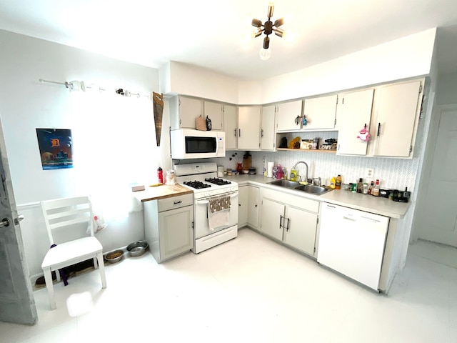 kitchen featuring tasteful backsplash, sink, gray cabinetry, and white appliances