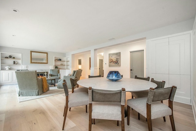 dining room featuring built in shelves and light hardwood / wood-style floors