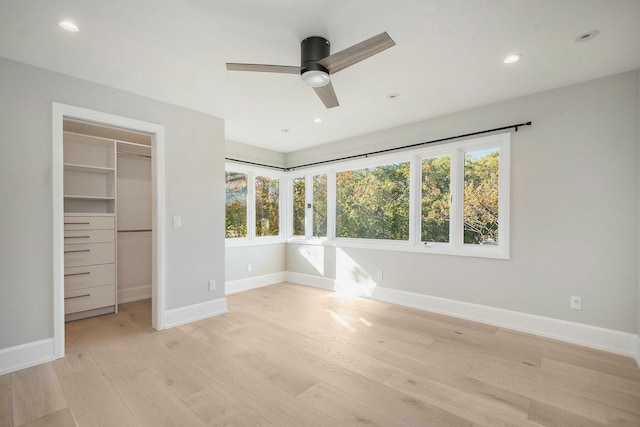 unfurnished bedroom with a walk in closet, ceiling fan, light hardwood / wood-style floors, and a closet