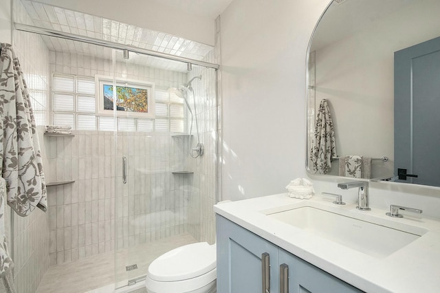 bathroom featuring a shower with shower door, toilet, and vanity