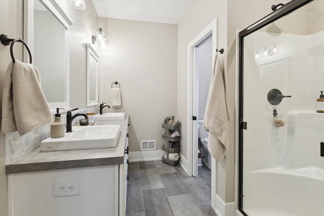 bathroom with toilet, a shower with shower door, and vanity