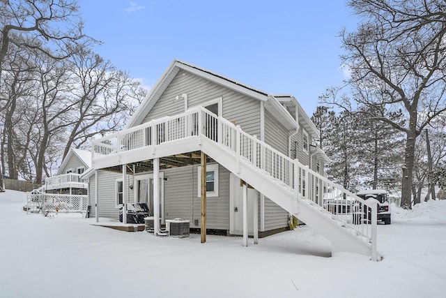 snow covered back of property featuring central AC unit and a deck