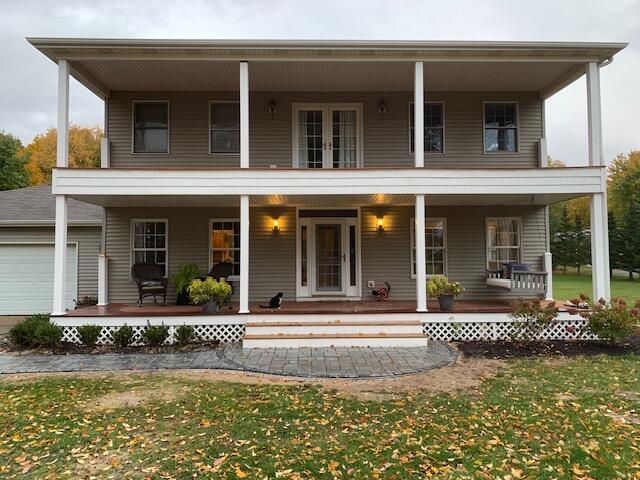 exterior space with covered porch, a yard, french doors, and a garage