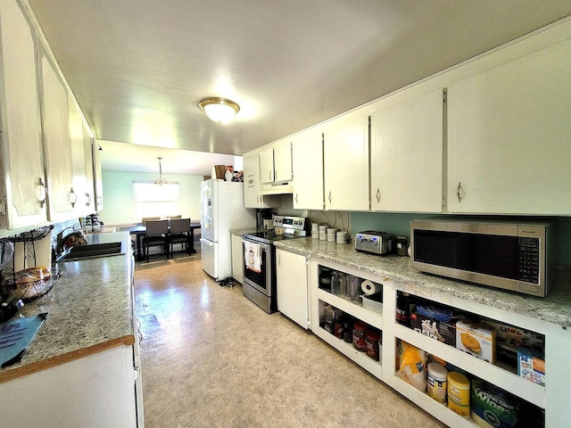 kitchen with white cabinets, stainless steel appliances, light stone counters, and sink