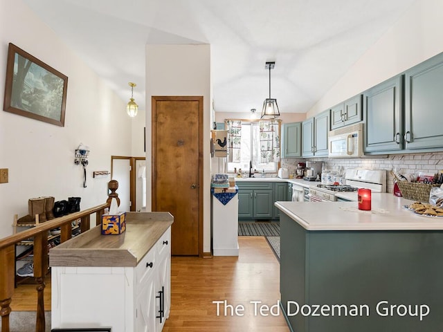 kitchen with vaulted ceiling, decorative backsplash, hanging light fixtures, light hardwood / wood-style floors, and white appliances