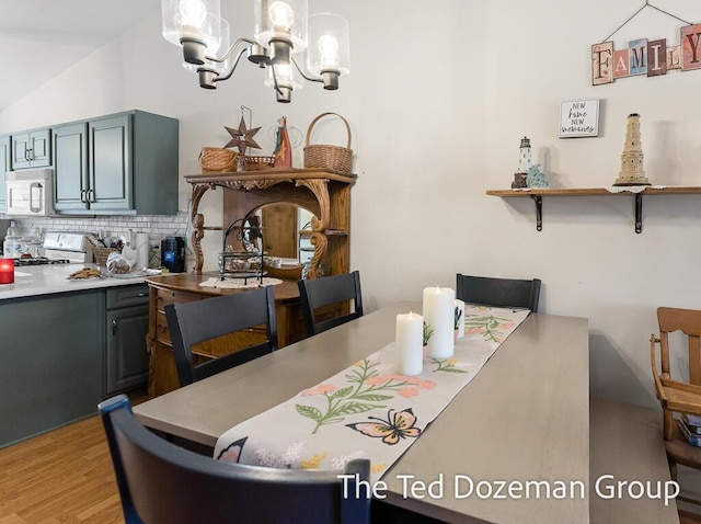 dining room featuring vaulted ceiling, light wood-type flooring, and a chandelier