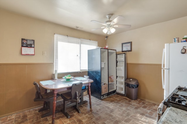 dining room with wooden walls and ceiling fan