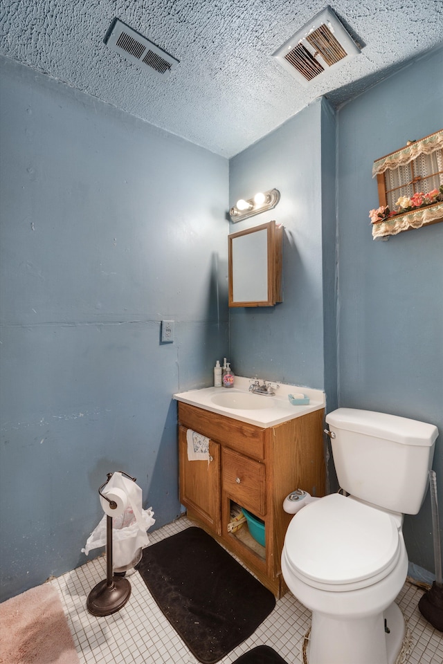 bathroom featuring vanity, toilet, tile patterned flooring, and a textured ceiling