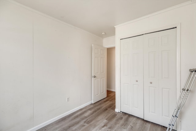 unfurnished bedroom with crown molding, a closet, and light hardwood / wood-style flooring