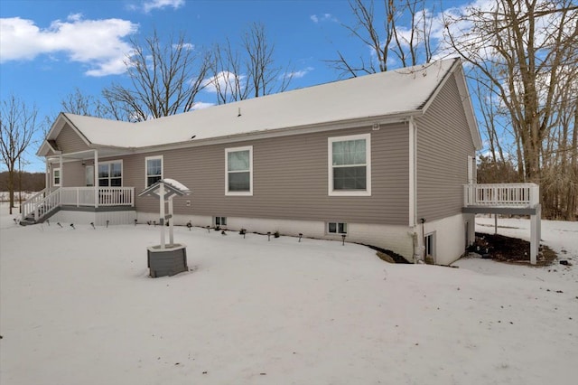 snow covered house featuring central AC and a porch